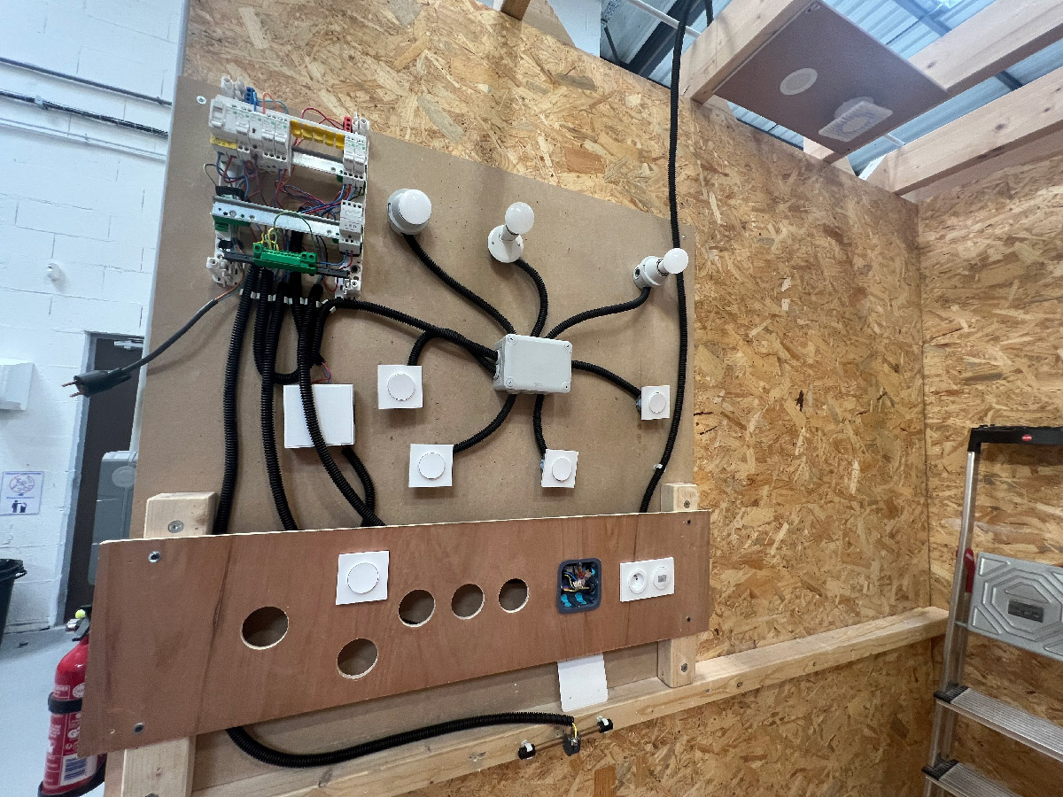 Installation of a doorbell triggered by a push-button, a spotlight and a mechanical ventilation system activated by a motion sensor, and a plug socket.